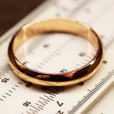 A gold wedding band placed on ring measuring scale.