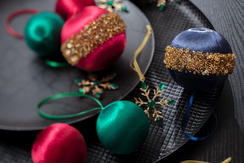 Some fabric baubles in rich green, pink and blue tones with gold glitter.