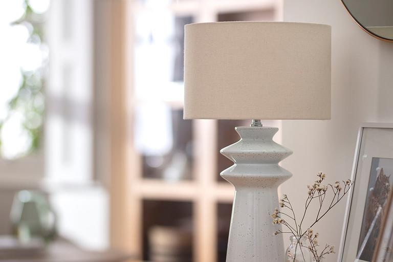 White table lamp on side board next to reading glasses.