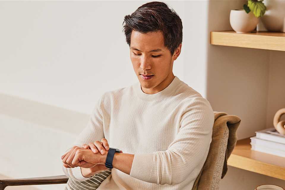 Man sitting and looking at his Fitbit watch.