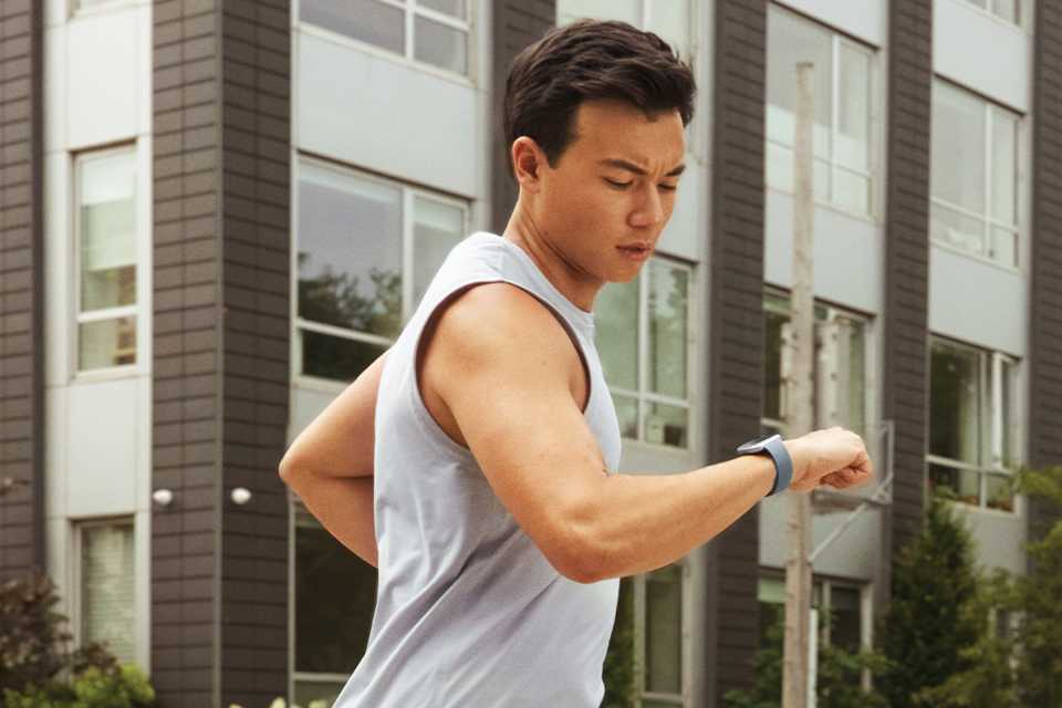 Man running while looking at his Fitbit watch.