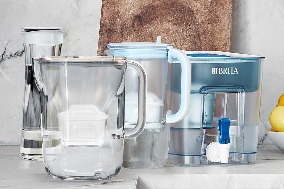 A BRITA carafe, glass jug and flow tank on a kitchen worktop with other things.