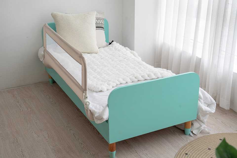 A Cuggl Bed Rail in grey fitted on a child's bed.