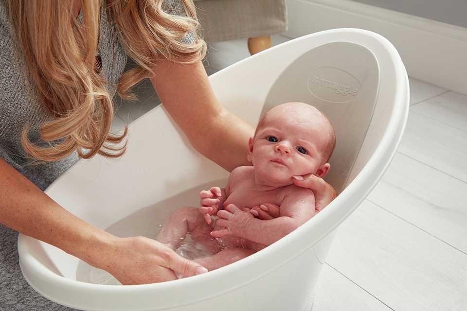 A baby being bathed in a Shnuggle Baby Bath.