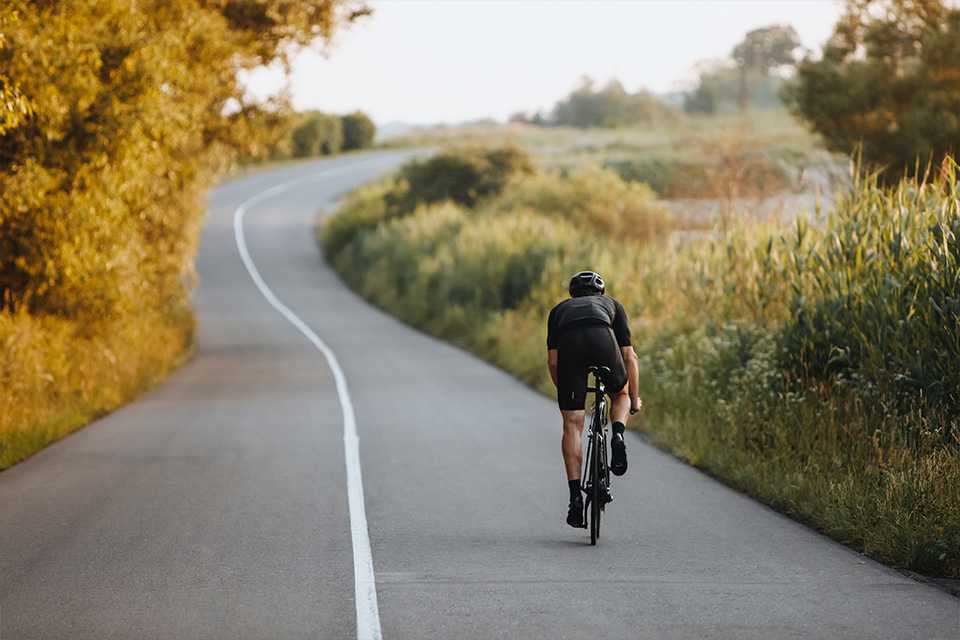 A man riding his road bike on a paved road.