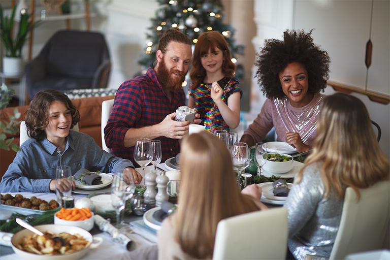 A family celebrating with a meal and gifts at a dining table.