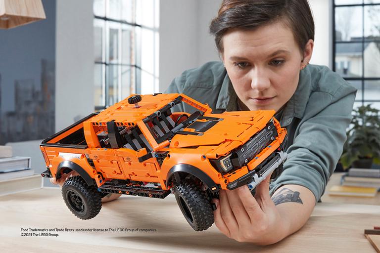 A man looks intently at a green Lego model Lamborghini racing car.
