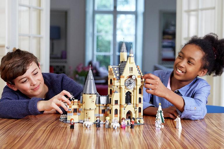 A boy and a girl playing with the LEGO® Harry Potter Hogwarts Clock Tower Toy on a kitchen table.