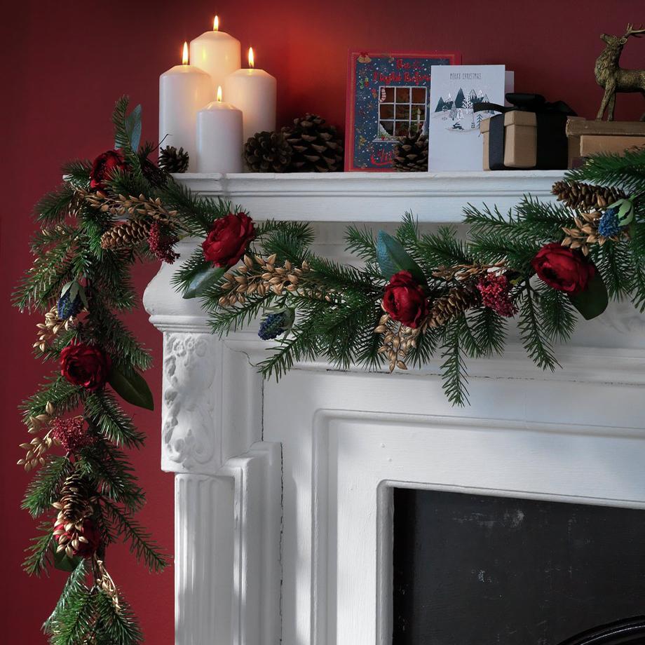 Green and red christmas garland on a mantlepiece.