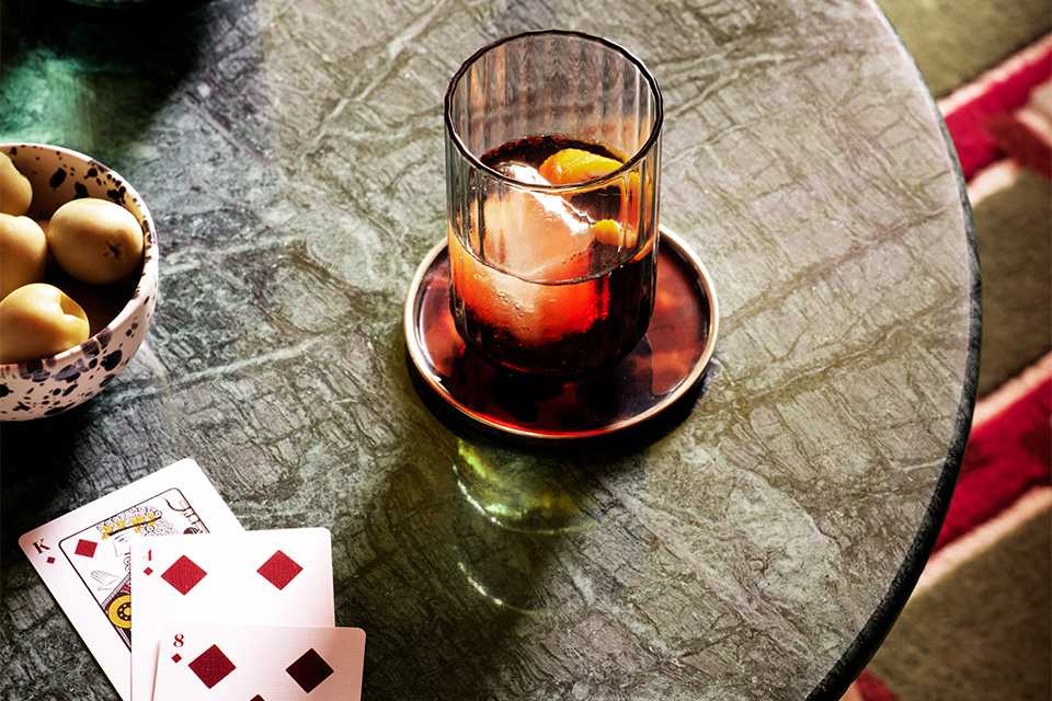 A glass of drink and playing cards on a wooden table.