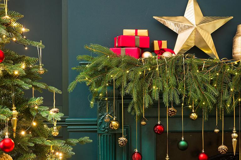 Image of a mentelpiece decorated in festive foliage and hanging baubles.