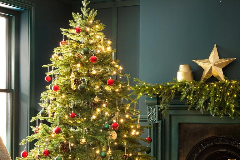Large green christmas tree with gold decorations and christmas presents underneath the tree.