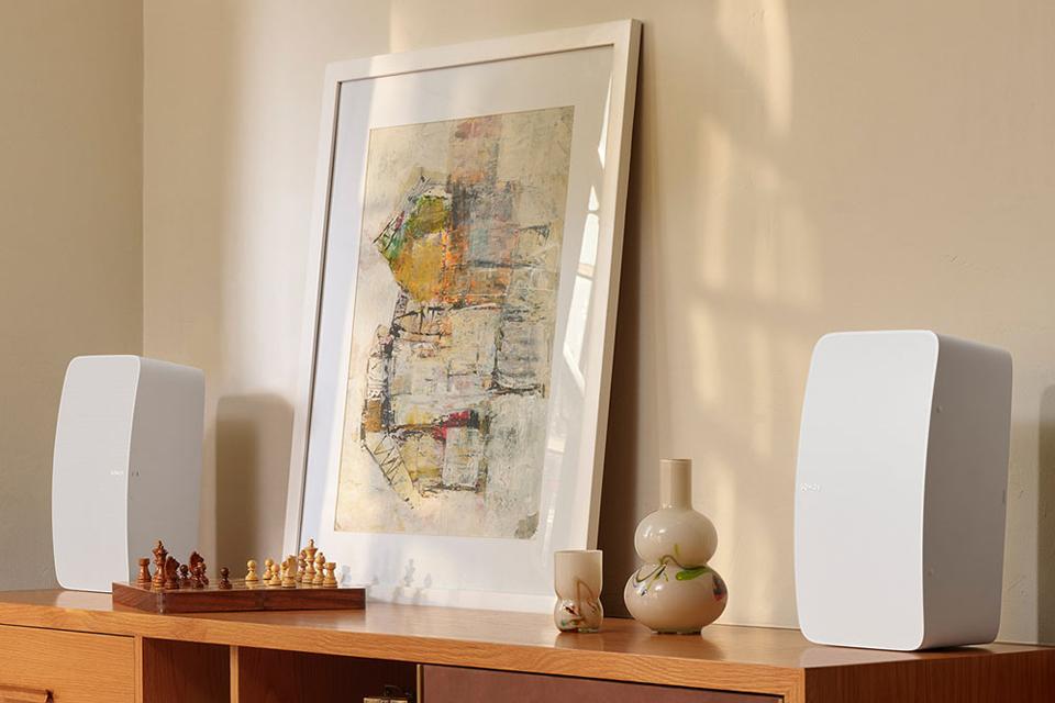 Two white Sonos speakers are shown at either end of a sideboard.