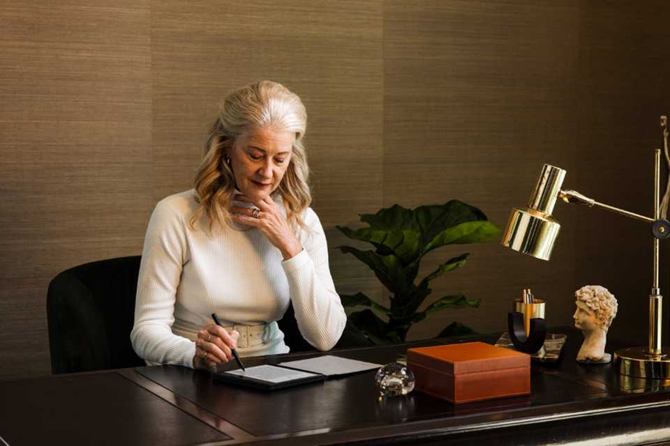 Elegant senior woman using Rakuten Kobo eReader in well-lit room.