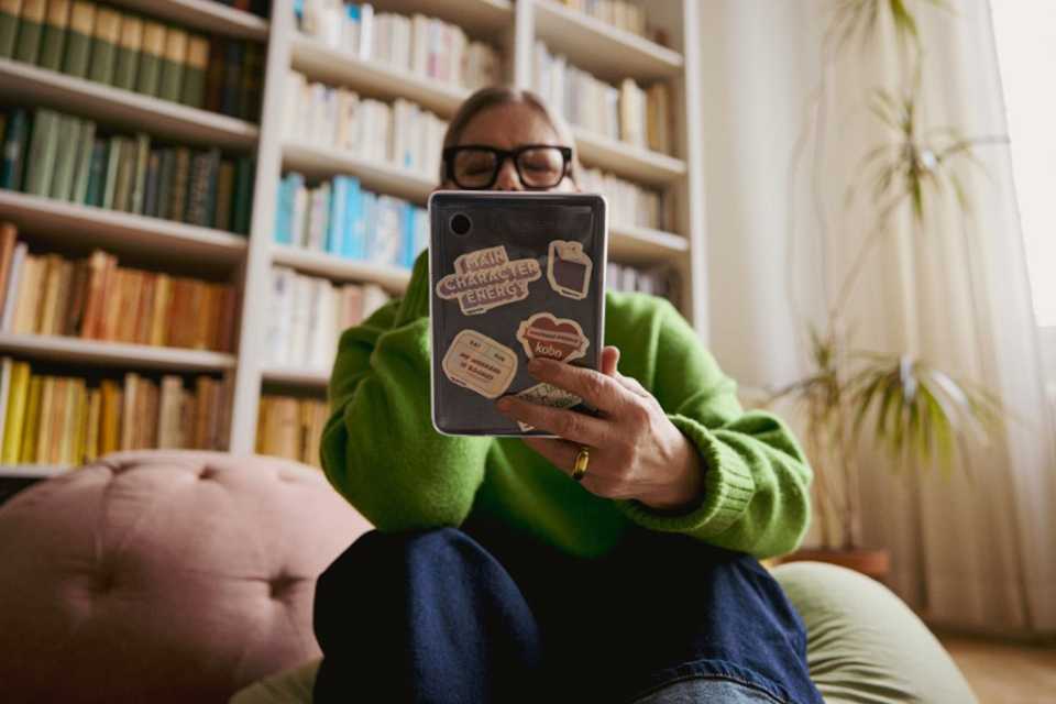 A person reading a Rakuten Kobo eReader in a cozy library.
