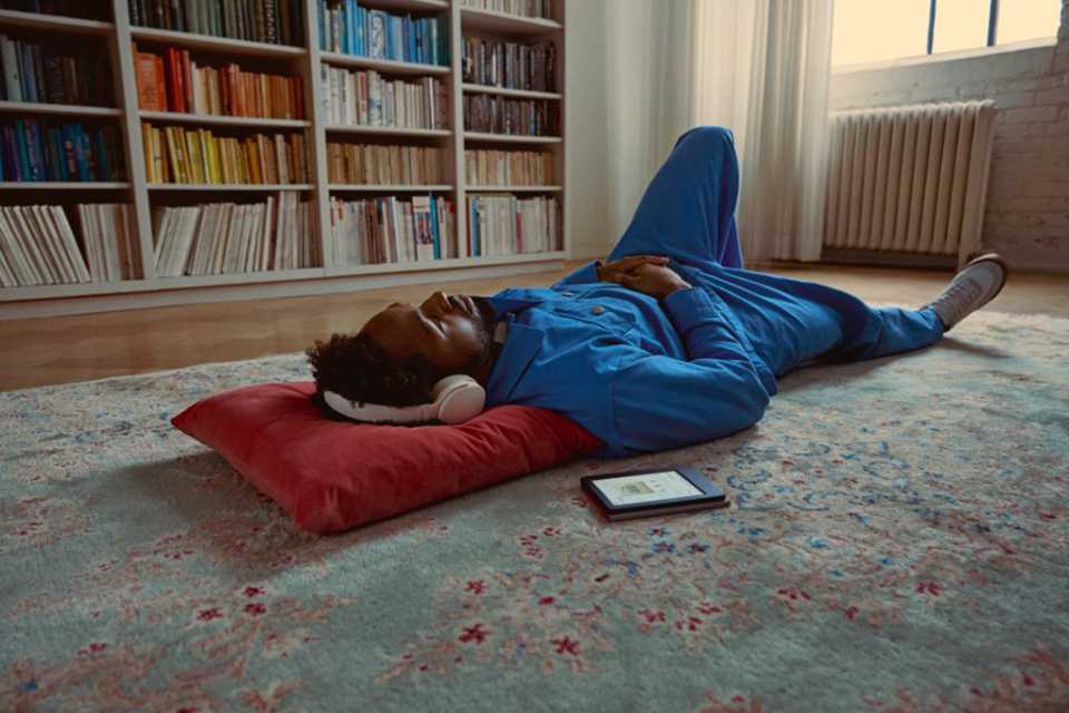 A person lying comfortably with a Rakuten Kobo Libra Colour eReader by their side.