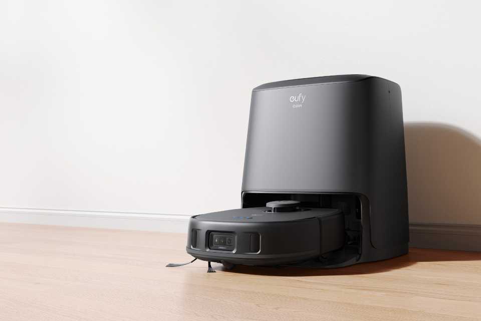 A eufy robot vacuum placed on a wooden floor.