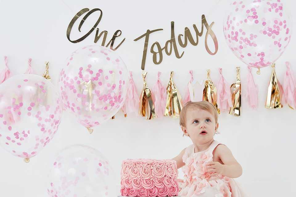 A baby's first birthday party with pink and gold themed decorations.