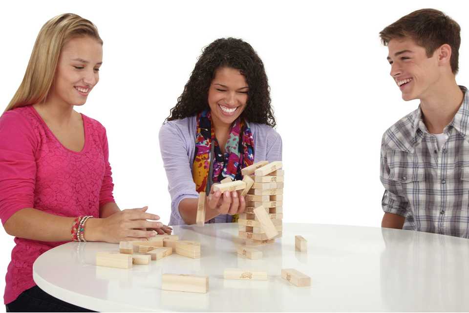 Three teenagers playing Jenga The Original Board Game from Hasbro Gaming.