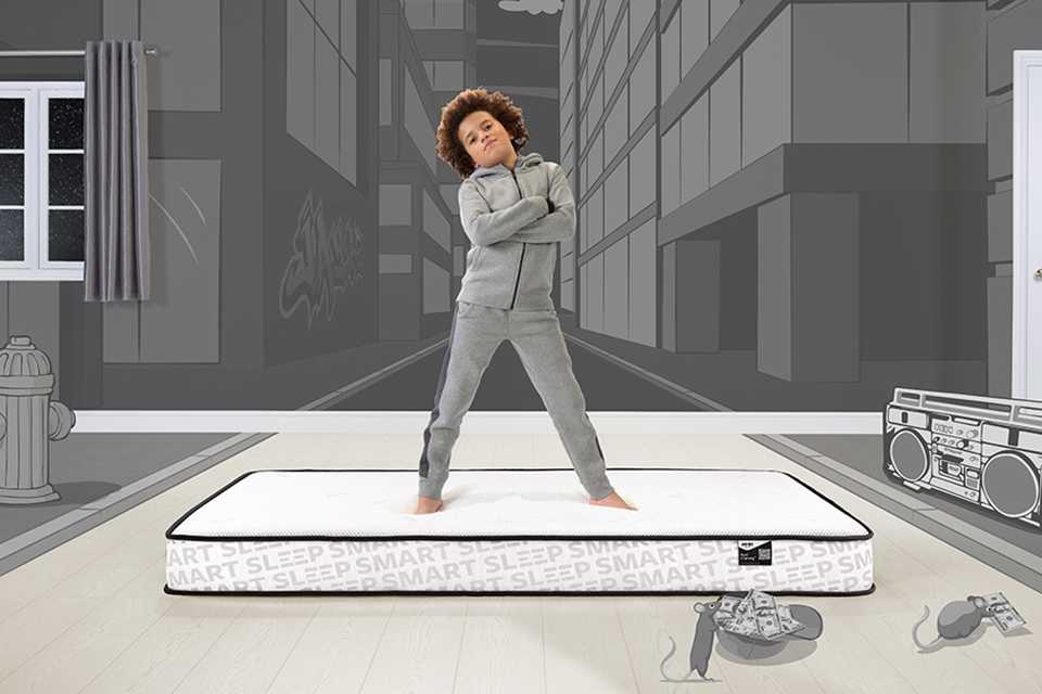 A kid standing on a Jay-Be® Bunk mattresses with folded arms.
