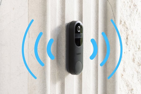 Black ring door bell on outdoor wall next to front door for security.