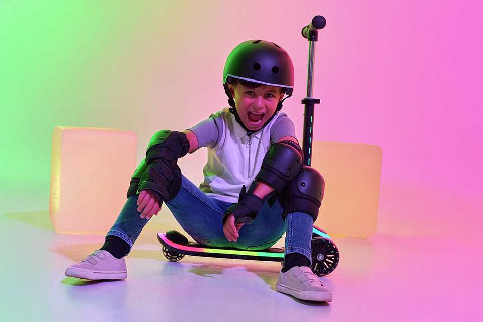 A boy sitting on a Zinc Sunshine Light Up 3 wheel scooter in black colour.