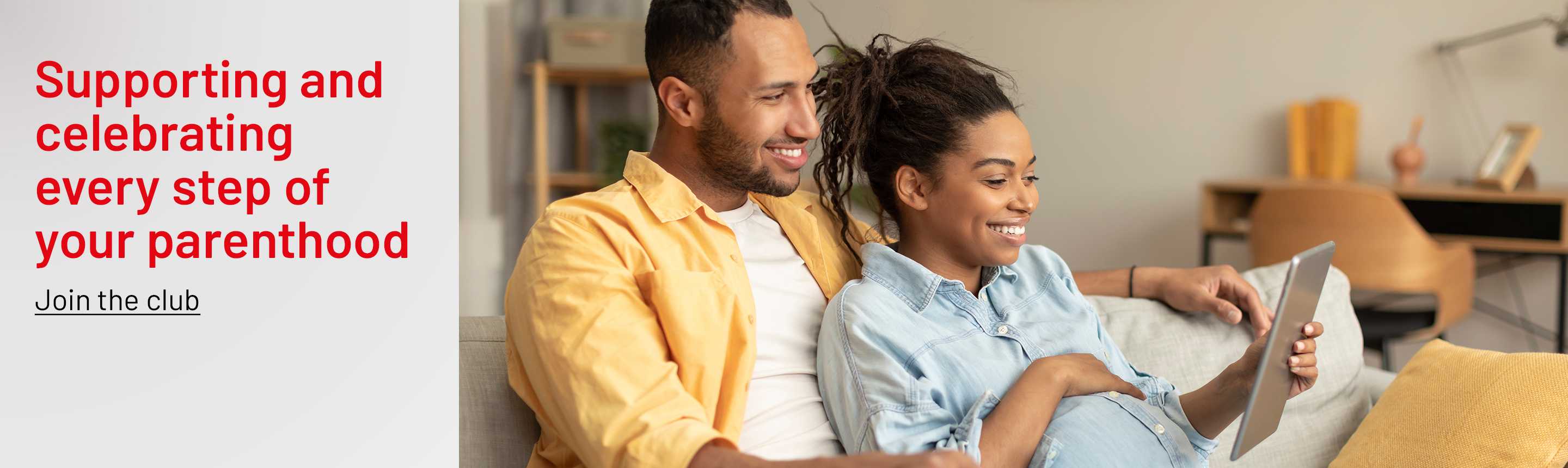 A pregnant couple looking at a tablet for baby related information.