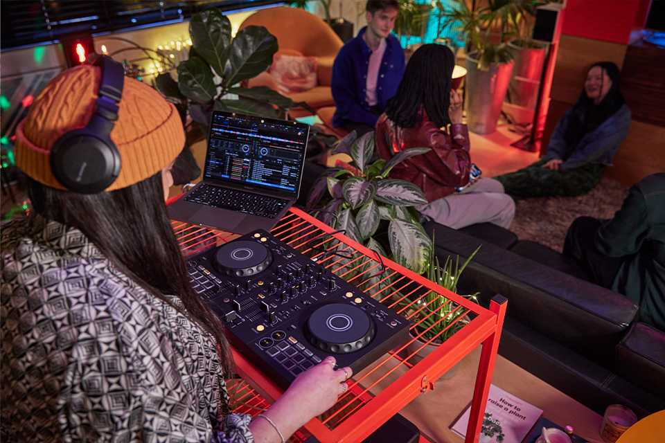 A side shot of DJ using a Pioneer DJ controller at a party.