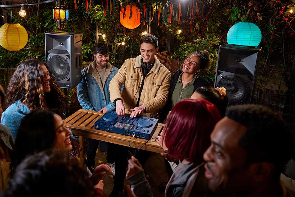 A young man DJing at a party using the Pioneer OMNIS-DUO DJ controller.
