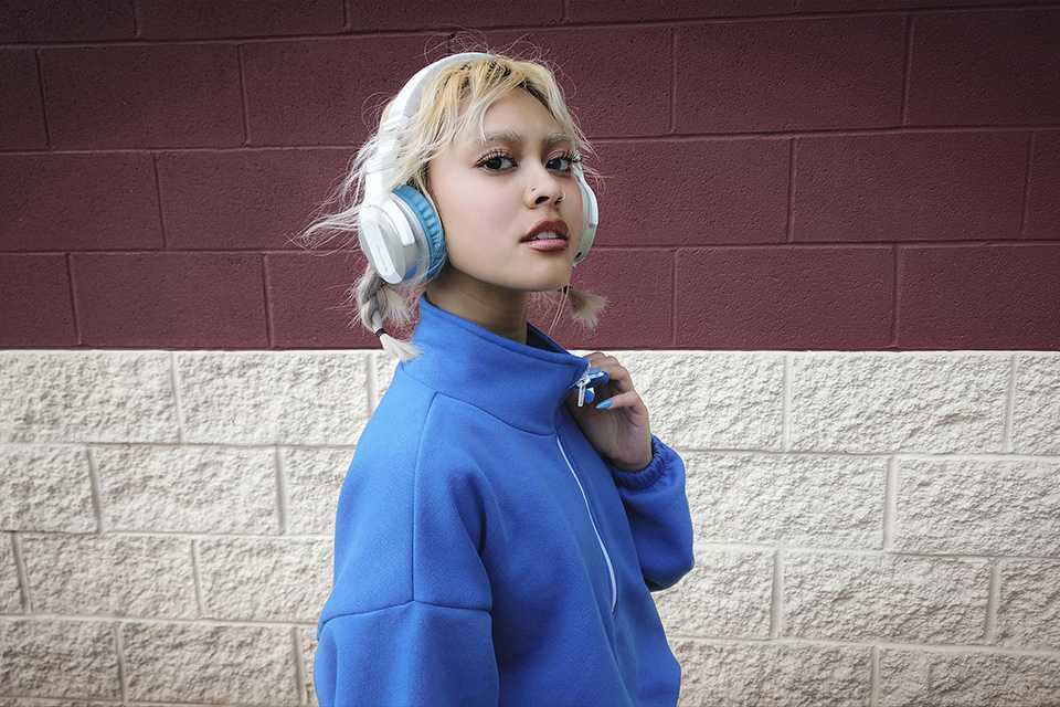 A woman wearing Pioneer blue headphone and listening to music.