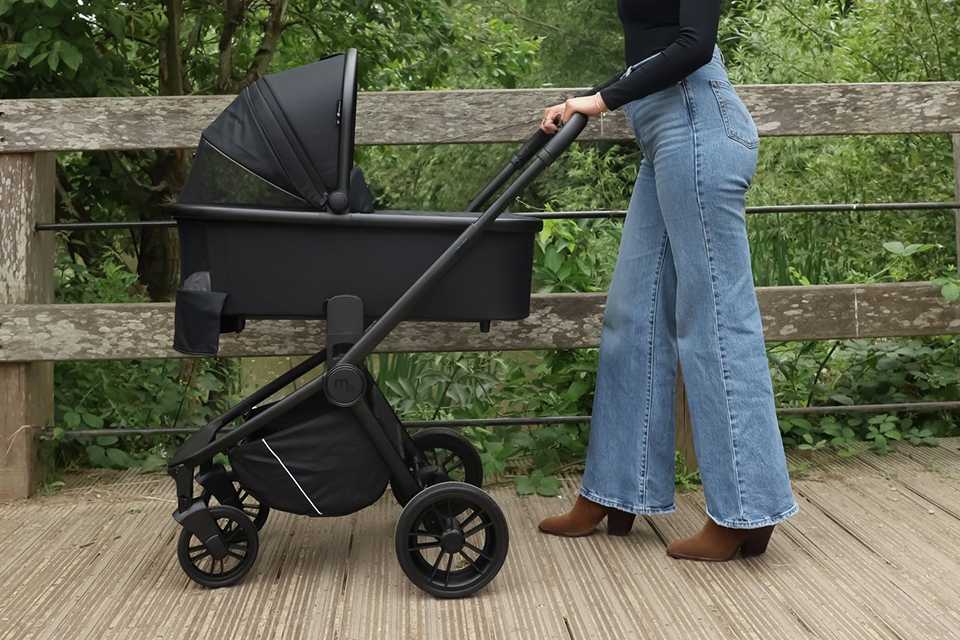 A mother pushing a My Babiie MB450I Travel System - Black.