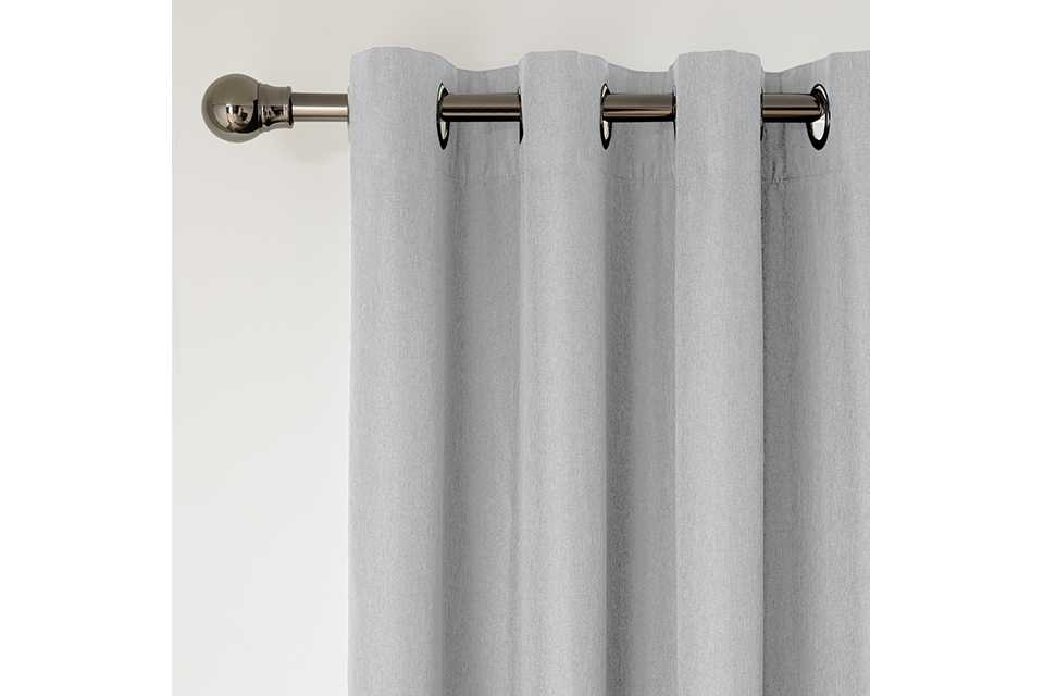 A grey curtain on a silver iron finish curtain pole.