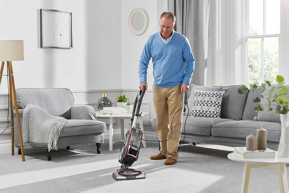 A man using a vacuum cleaner to clean the floor.