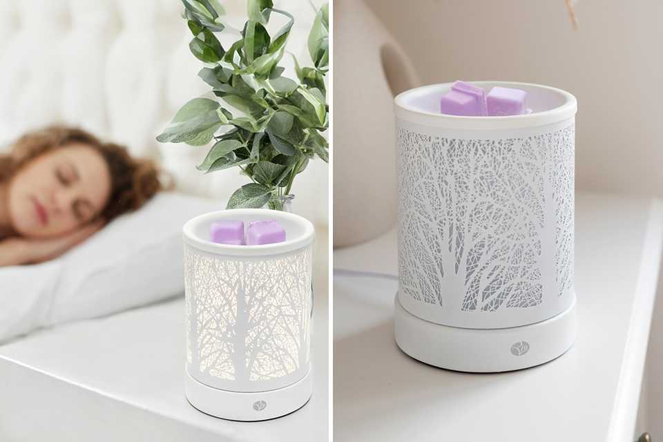 An electric diffuser on a table near a bed.