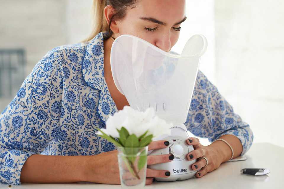 A woman using a sauna machine for facial sauna.