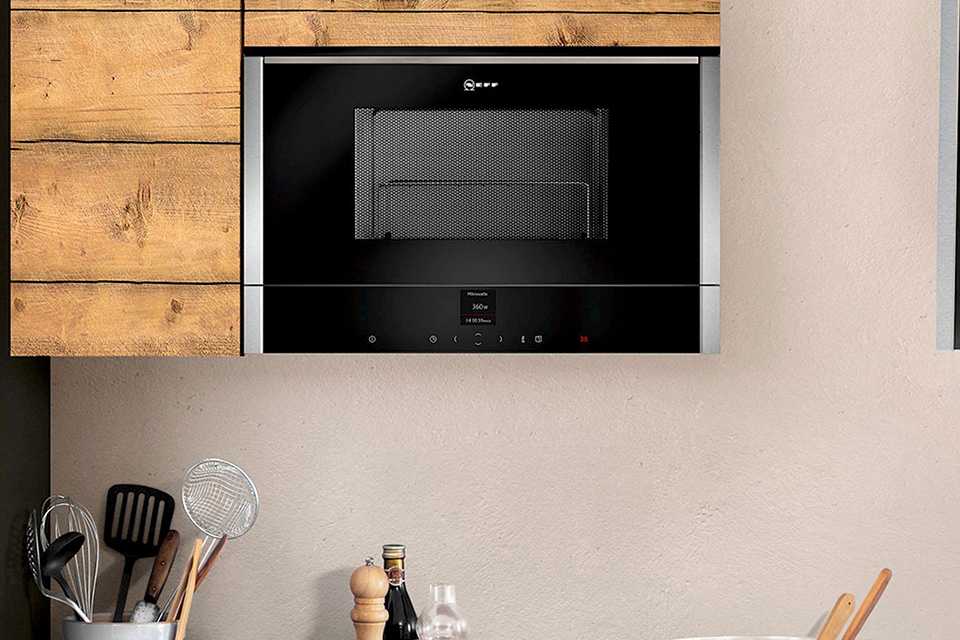 A NEFF microwave mounted inside a wooden shelf.