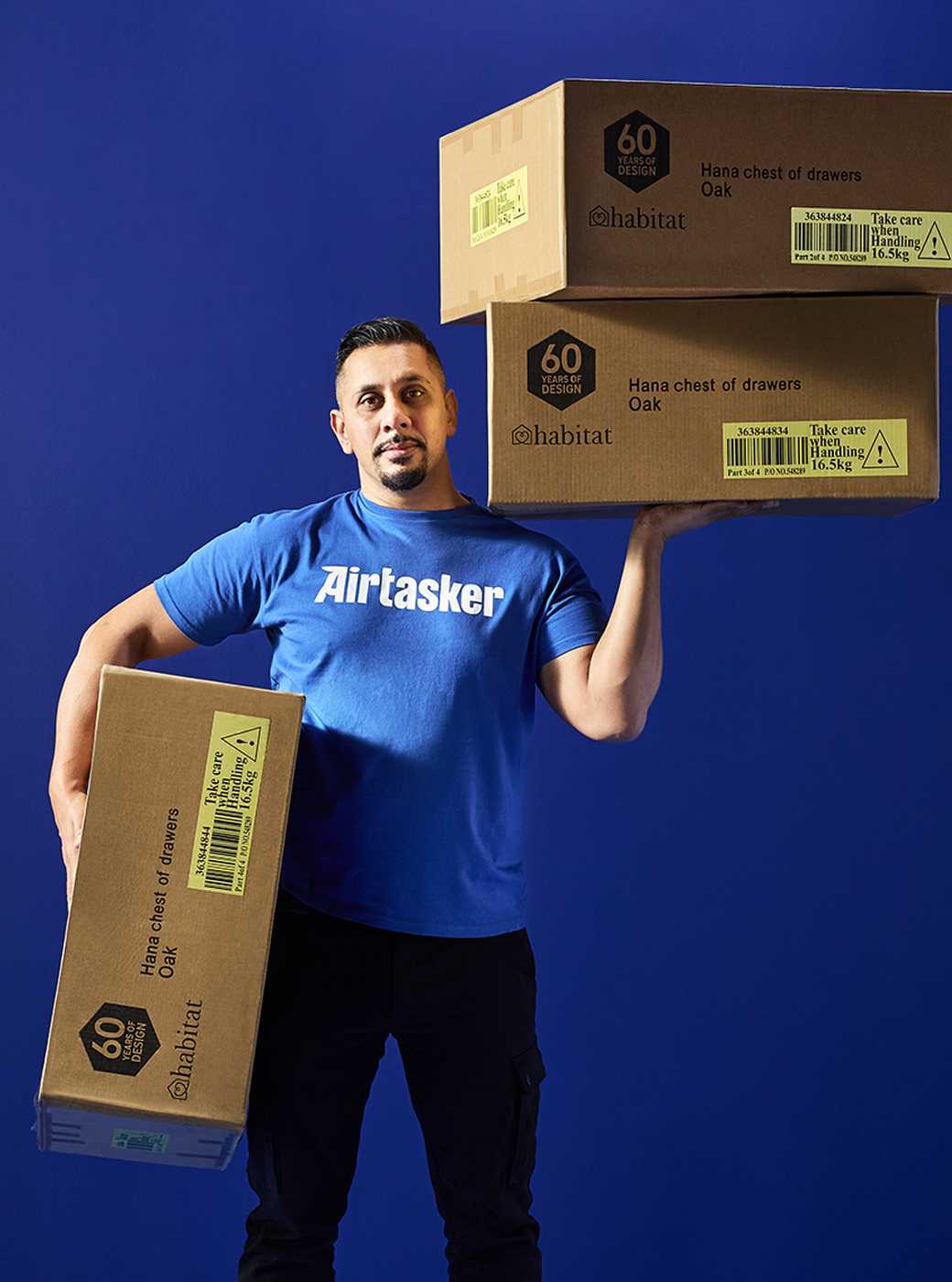 Air tasker man holding cardboard delivery boxes ready to unbox and build a flat pack.