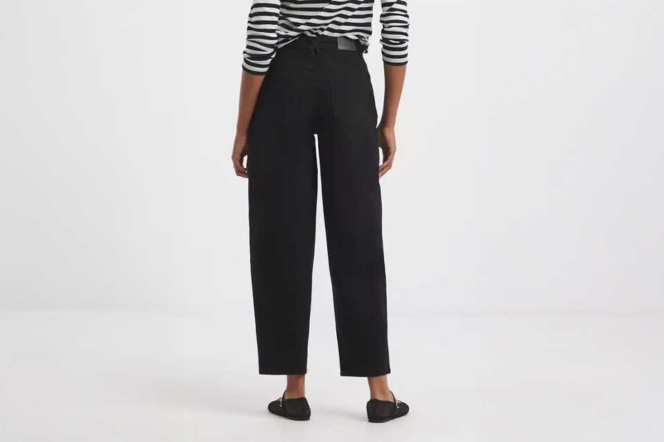 Person wearing a black-and-white striped long-sleeve top paired with high-waisted black straight-leg jeans and black flat shoes.