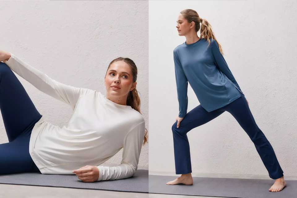 Person lying on a yoga mat, wearing a long-sleeve white top and navy leggings, holding one leg bent, and a person standing in a wide lunge pose on a yoga mat, wearing a long-sleeve blue top and navy pants.