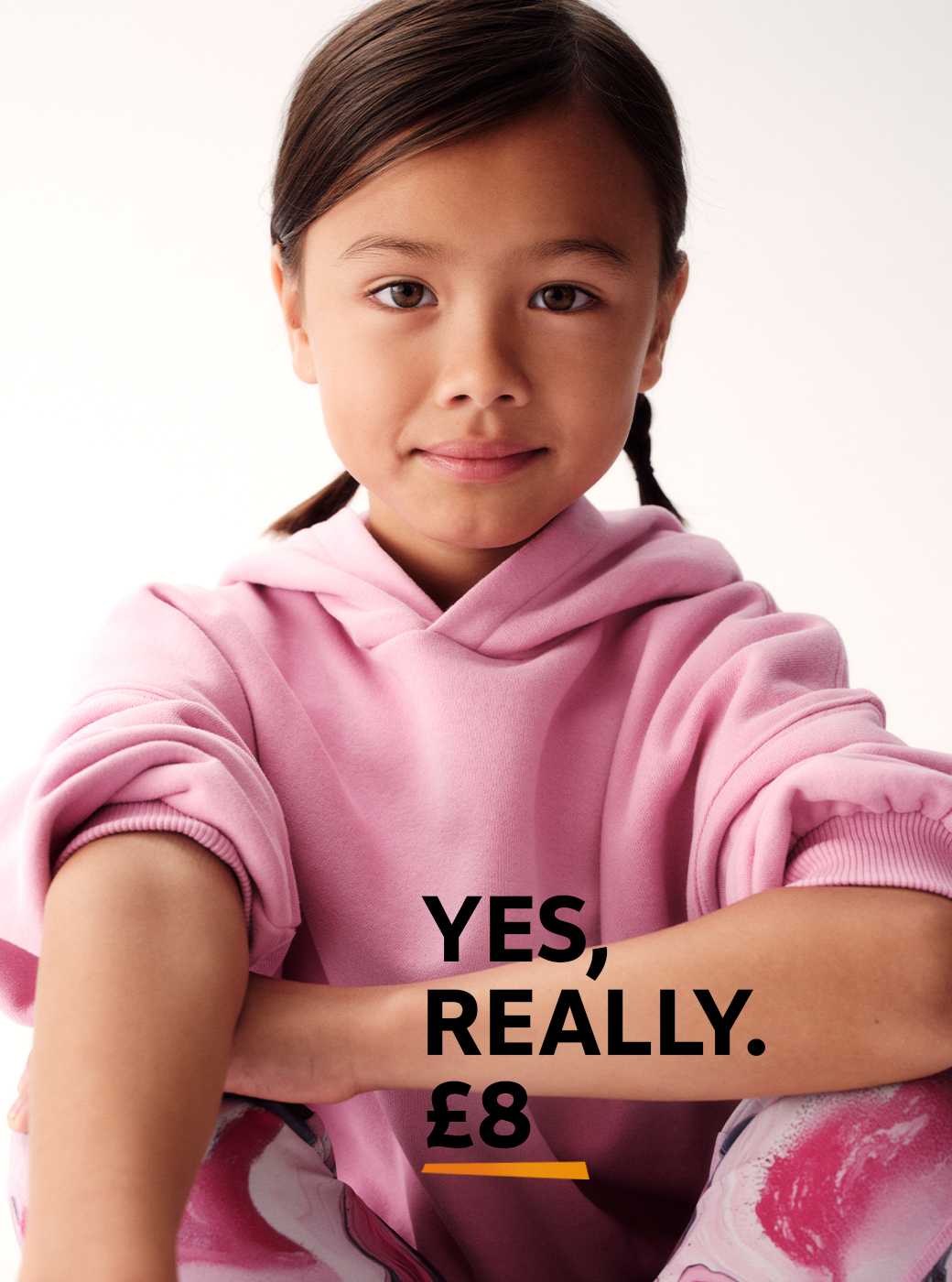 Person wearing a light pink hoodie with rolled-up sleeves and leggings featuring a pink, white, and black marble pattern, seated against a plain light background.