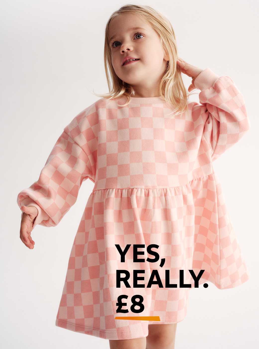 Young girl earing a neutral jacket with pink hearts and a pink stripey top underneath.