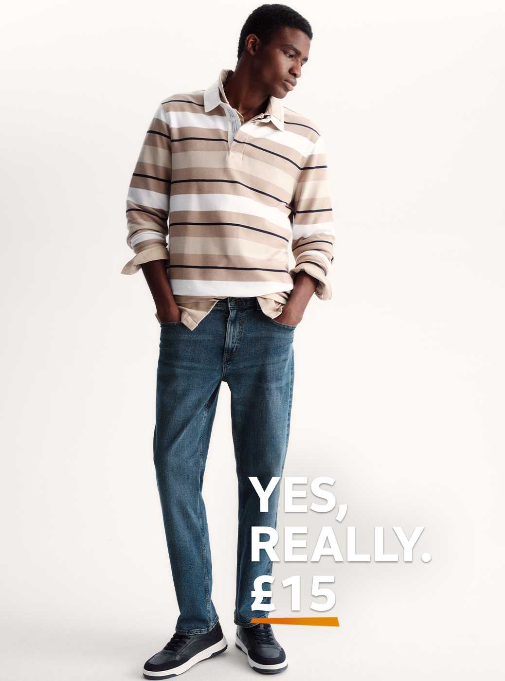 A man wearing a neutral striped sweatshirt with blue soft stretch jeans.