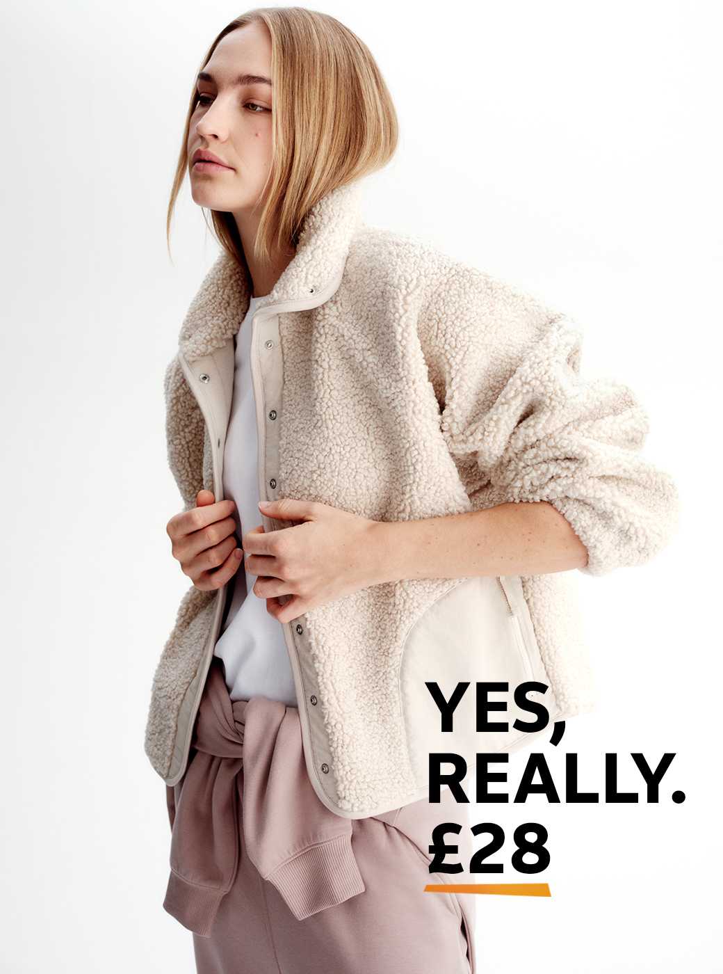 A woman wearing a soft borg jacket, with light pink jogging bottomsand a white t-shirt.