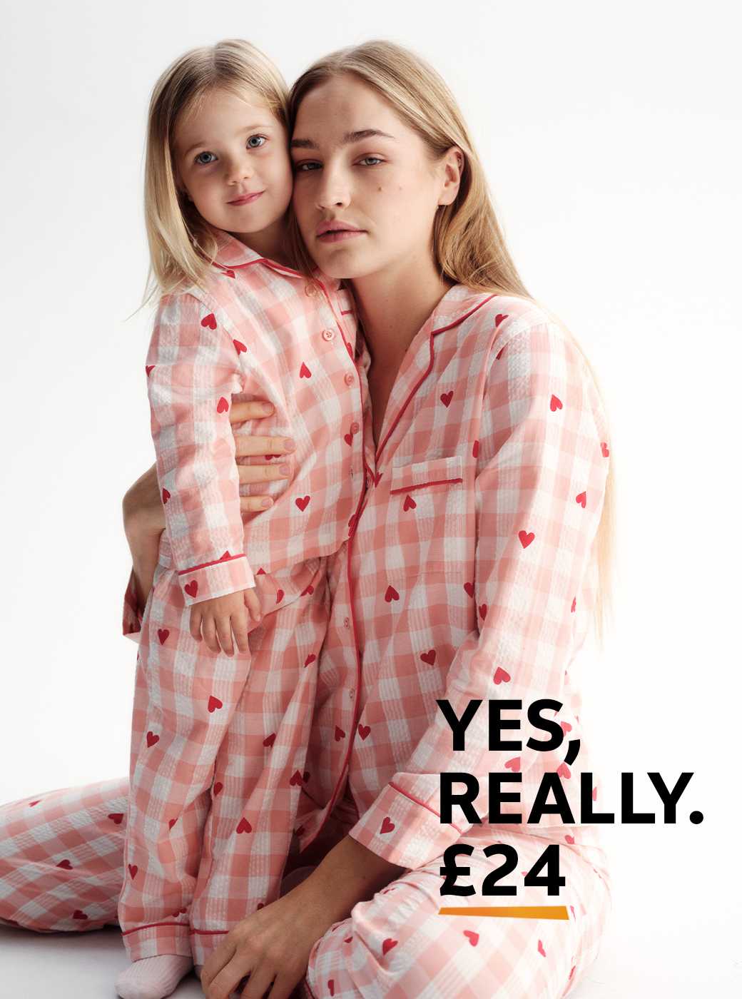 A woman wearing pink gingham seeksucker traditional pyjamas with red hearts.