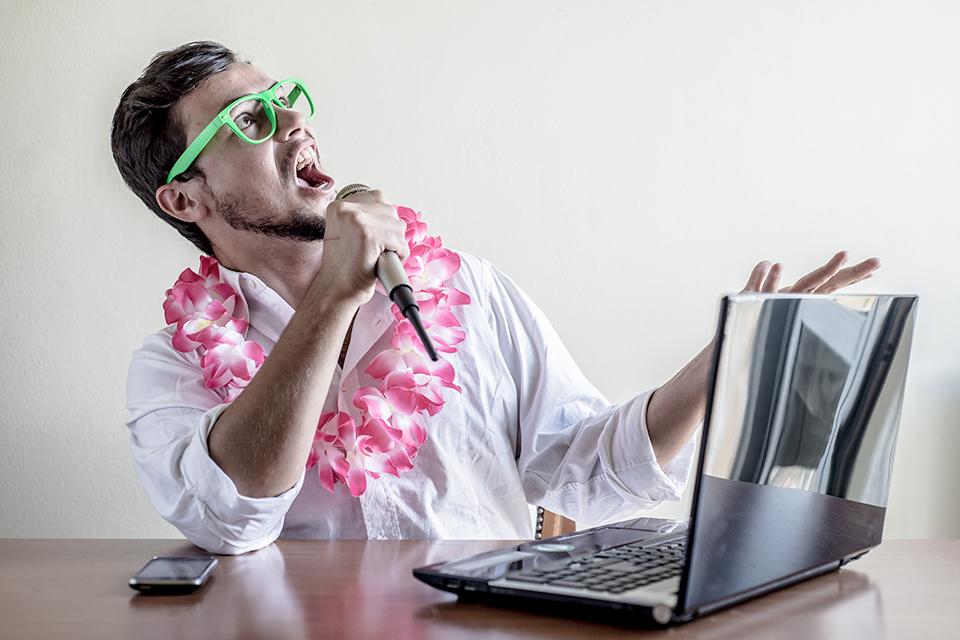Man in fancy dress singing into a laptop.