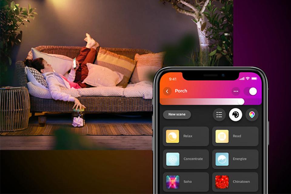 Woman lying on outdoor sofa with Philips Hue colour lights on.