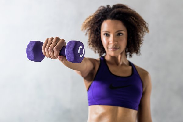 A woman exercising with a Opti Neoprene 3kg purple dumbbell.