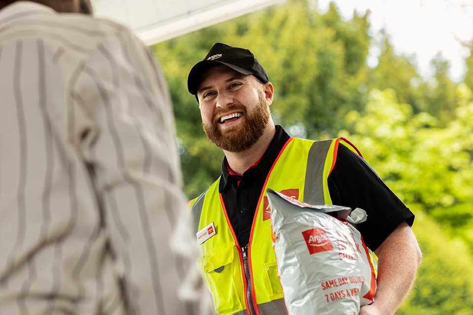 Argos employee passing over a package to customer on doorstep.