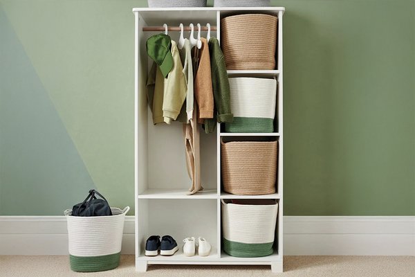 A white freestanding open wardrobe with decorative storage boxes against a green bedroom wall