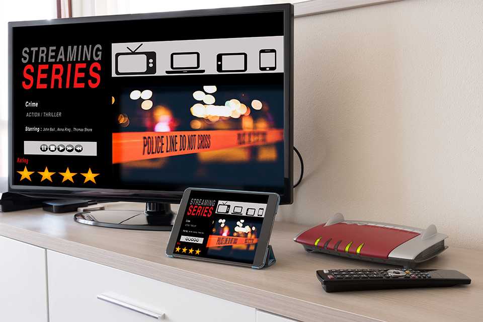 A smart TV, tablet, TV remote and a WiFi router placed on a TV unit.